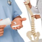 Close-up mid section of female doctor with pills and colleague by skeleton model over