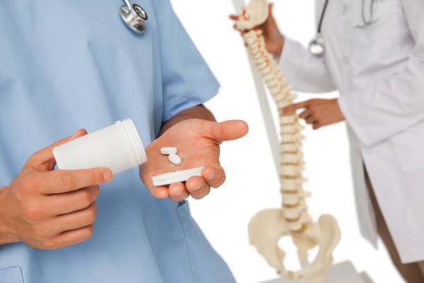 Close-up mid section of female doctor with pills and colleague by skeleton model over